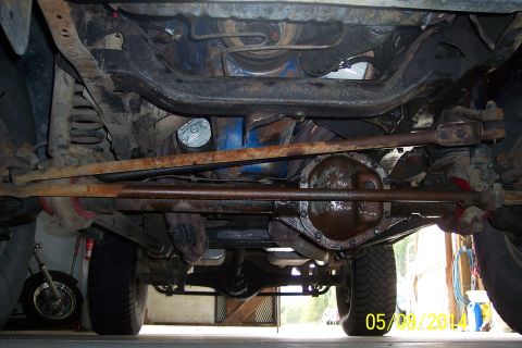 1978 Ford Bronco - A low-angle shot reveals the rusty undercarriage of a vehicle, including its suspension and differential.
