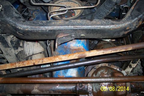 1978 Ford Bronco - A close-up view of the undercarriage reveals rusty components and a blue-painted engine part.