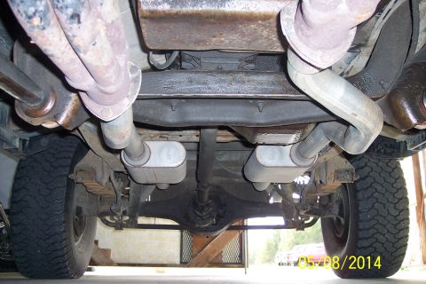1978 Ford Bronco - The underside of a vehicle reveals its exhaust system and suspension components.