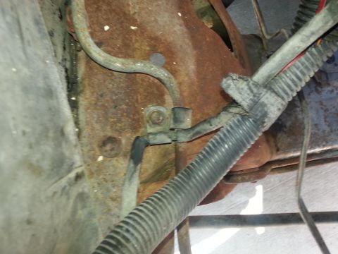 1994 Ford Bronco - Undercarriage view showing brake lines and a protected wiring harness attached to a rusty frame.
