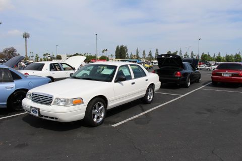 White Ford Crown Victoria parked at angle in a sunny car show lot