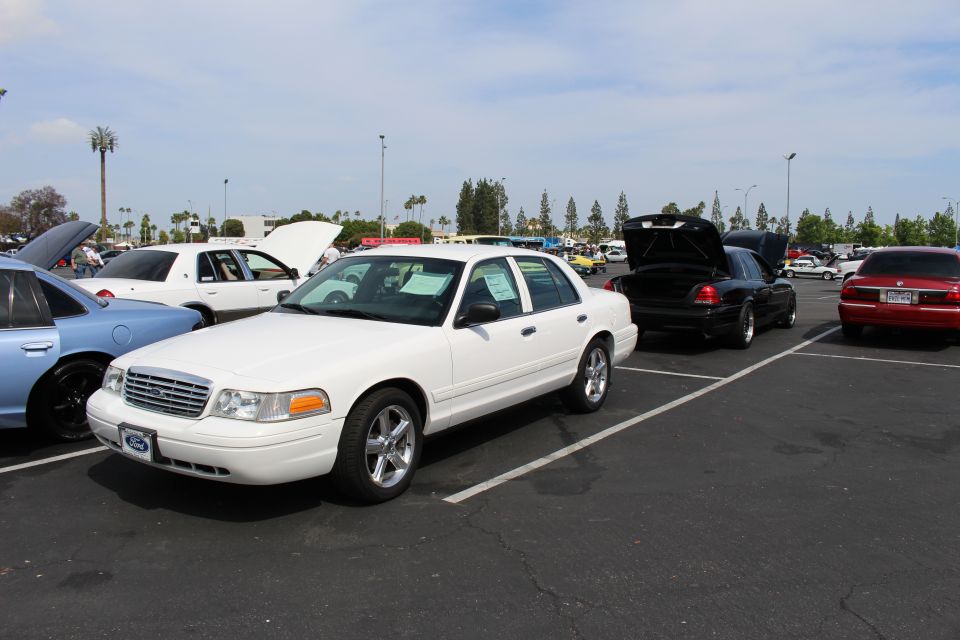 White Ford Crown Victoria parked at angle in a sunny car show lot