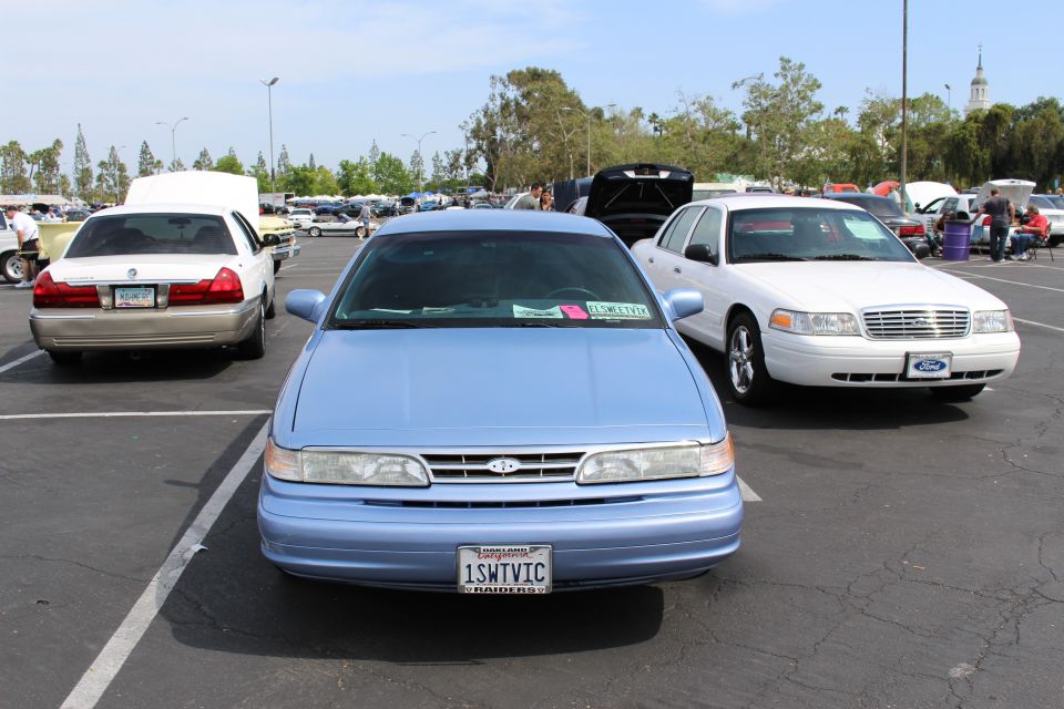 Front view of a light blue Ford sedan with white Crown Victoria beside it