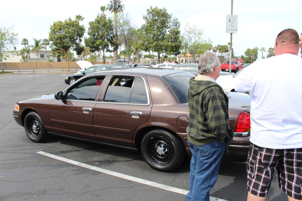 Brown Ford sedan parked as two men stand beside it in a parking lot