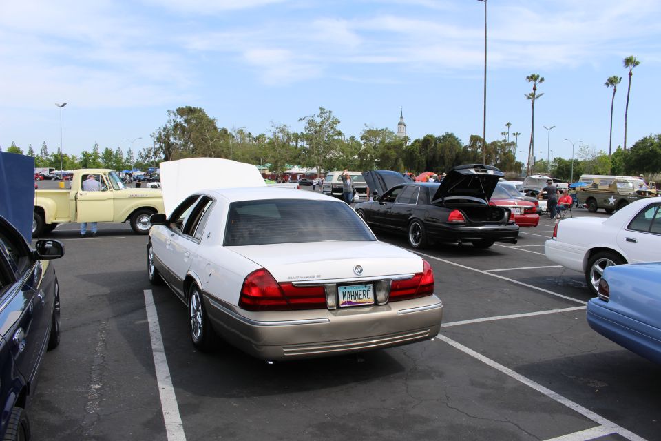Rear of a two-tone Mercury sedan parked in a busy car show lot
