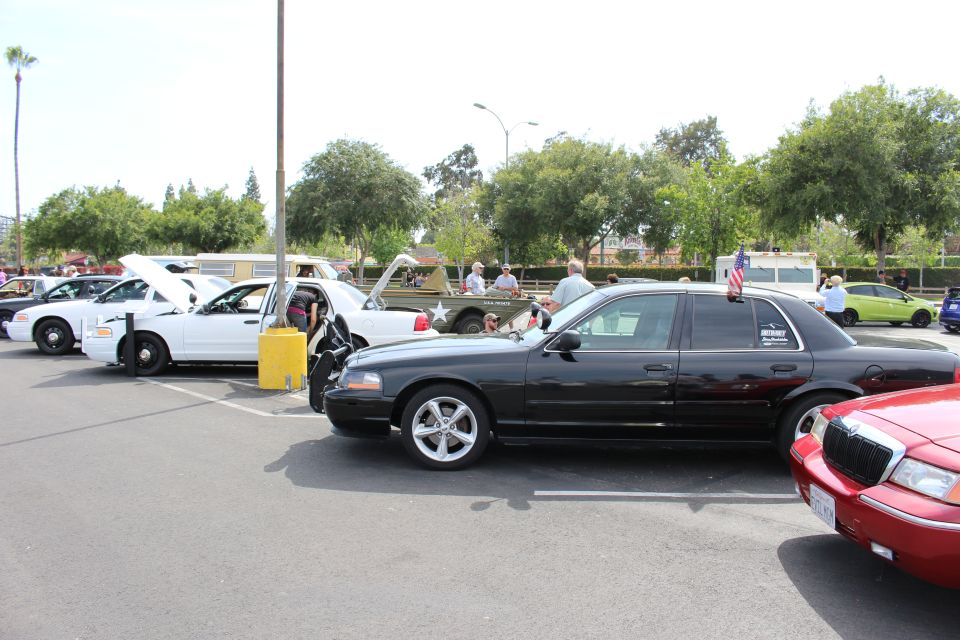 Black sedan with American flag parked near a row of white sedans