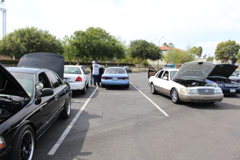 Black sedan with open trunk among parked cars in a car show lot
