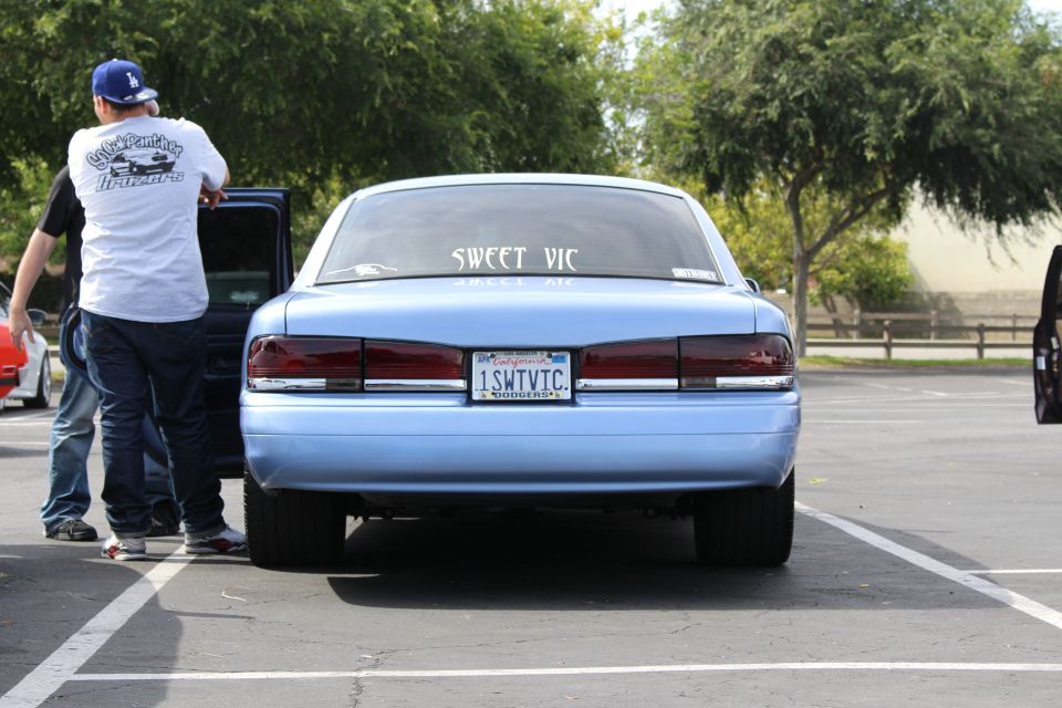 Rear of light blue SWEET VIC sedan with door open and a man beside it