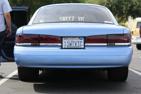 Close rear view of a light blue sedan with SWEET VIC lettering and DODGERS plate frame