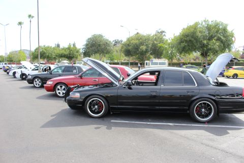 Black sedan with black wheels and red calipers in foreground, maroon car and yellow car behind