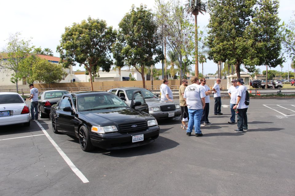 Black Ford sedan parked at angle with group of people standing beside it in parking lot