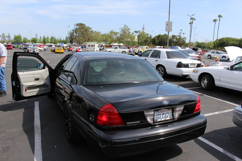 Black Ford sedan with open driver door and tan interior, California plate 6GLC676, in busy lot