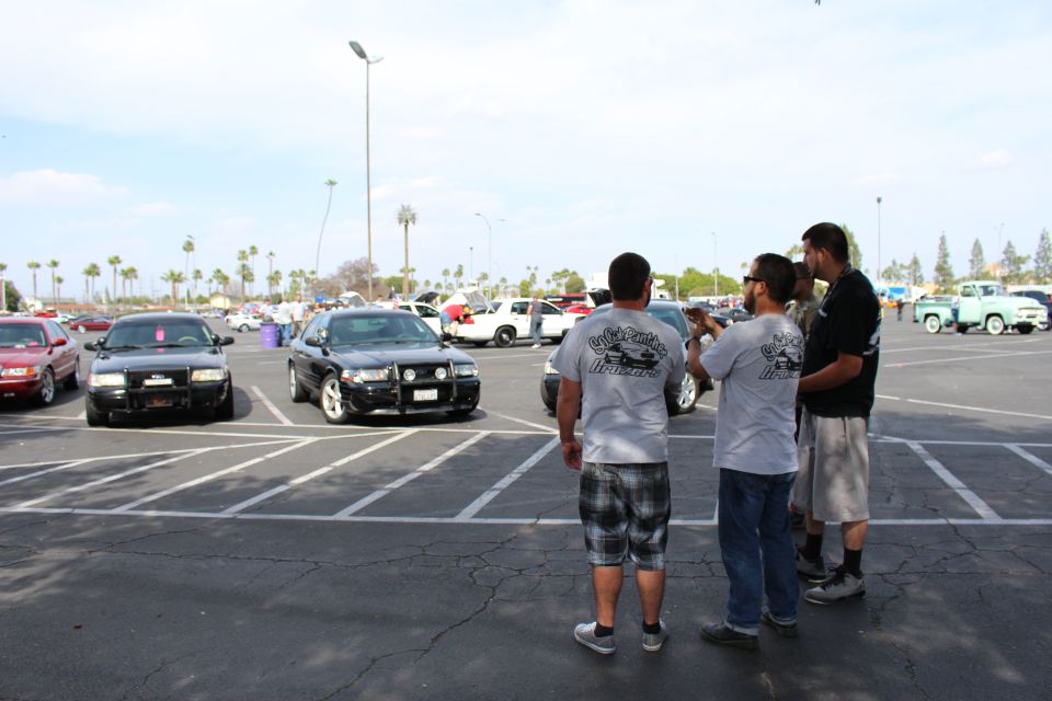 Group of men photographing a black sedan with brush guard in a parking lot car meet
