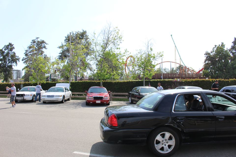 Black sedan turning in a lot with a roller coaster visible behind a hedge