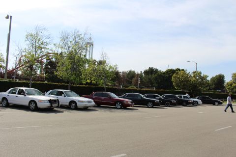 Lineup of parked sedans as a person walks across the empty lot