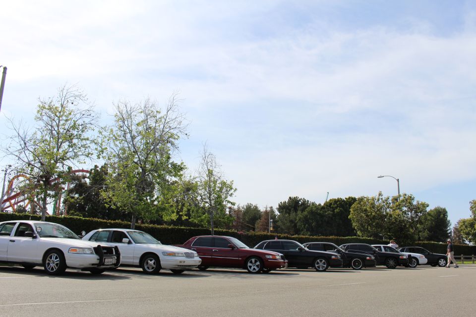 Diagonal view down a row of parked sedans with a coaster in the distance
