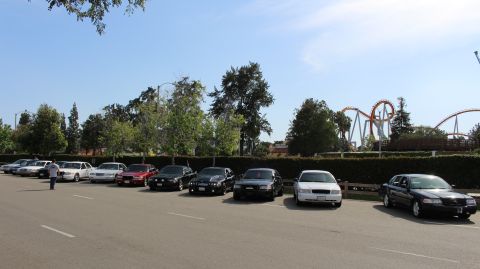 Long row of sedans parked in a lot under a clear blue sky