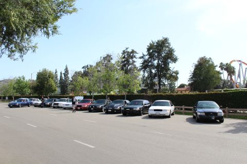 Row of parked sedans along a wide paved lot under blue sky