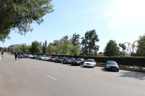People walking past a row of parked sedans in a lot
