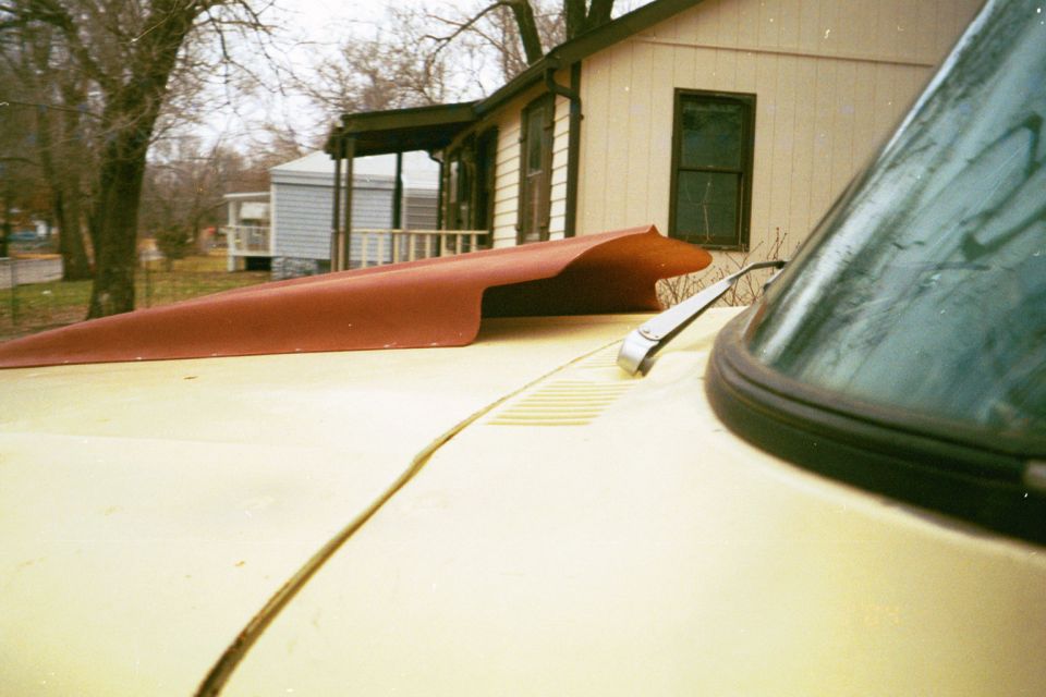 Yellow car hood with a red aftermarket hood scoop and a windshield wiper