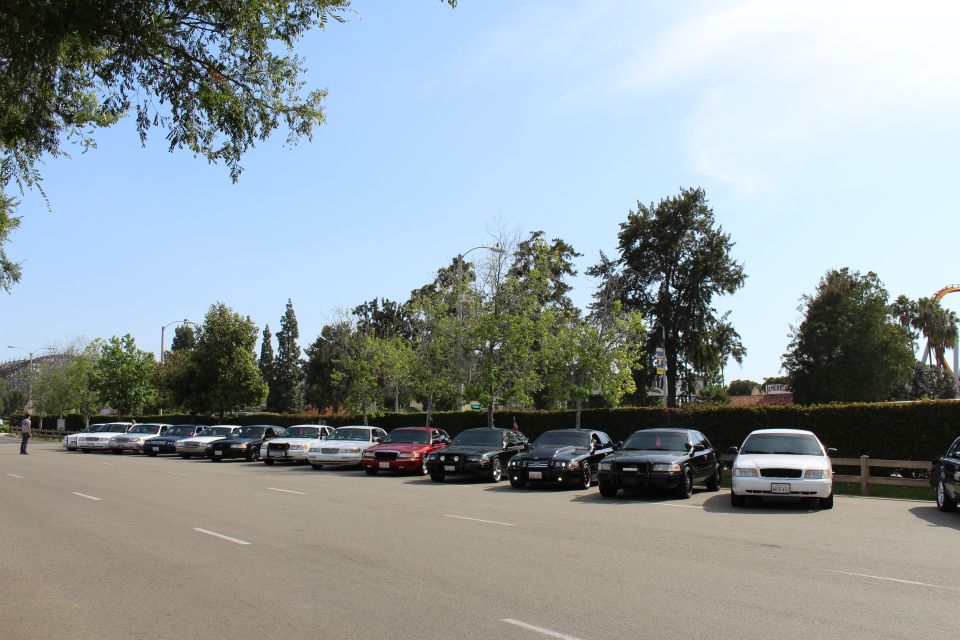 Line of parked sedans along a lot under a partly cloudy sky