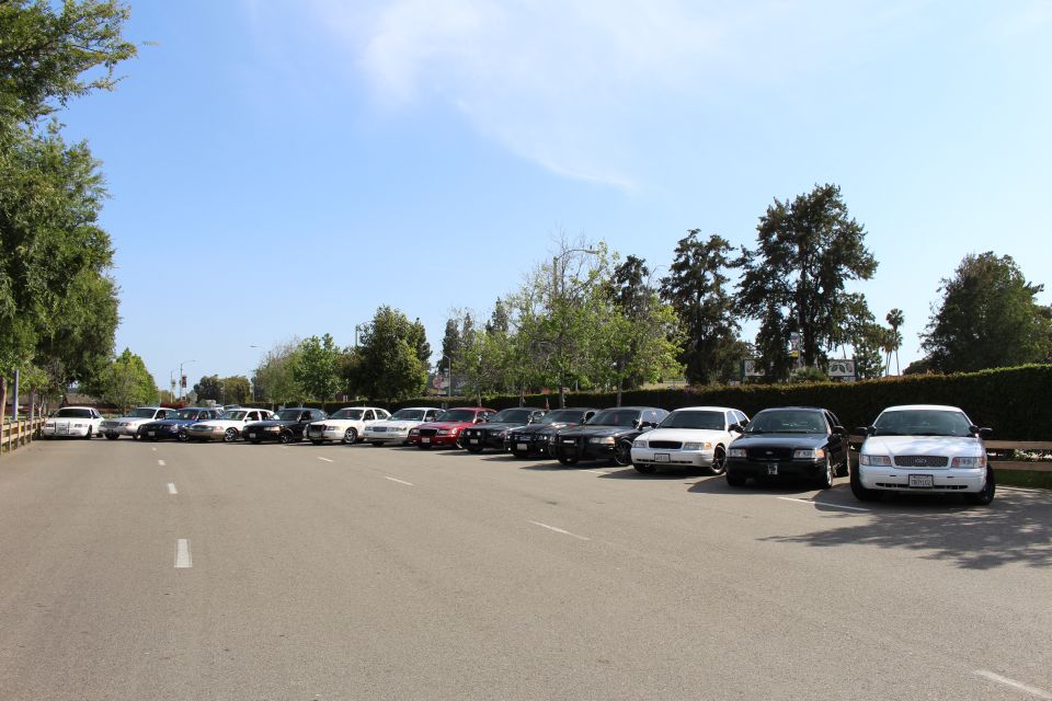 Row of parked sedans across a paved lot with white and black full-size cars