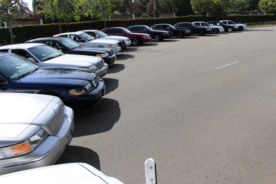 Row of parked sedans along a hedge with a silver Mercury in the foreground