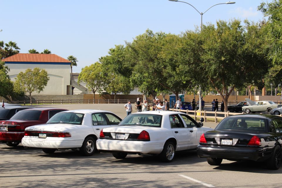 White and dark sedans parked at angles with a crowd of people in the background