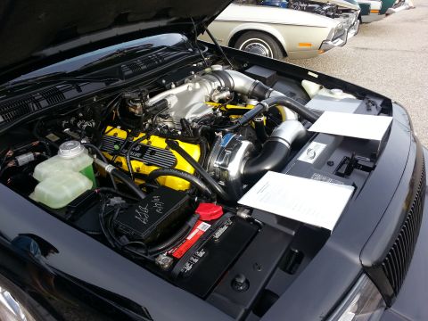 2003 Mercury Marauder - The engine bay of a black 2003 Mercury Marauder is open, revealing its yellow-accented engine and other components.