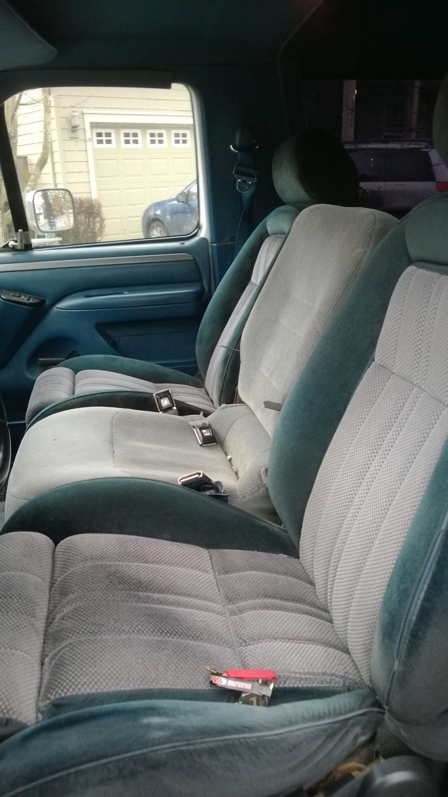 1994 Ford Bronco interior with blue and gray cloth seats and seatbelts