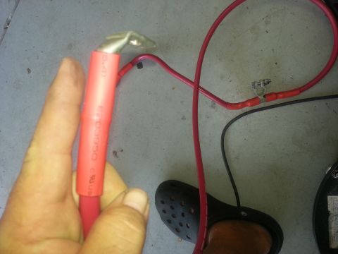 1994 Ford Bronco - Close-up of a red battery cable with a crimped terminal being held by a hand.