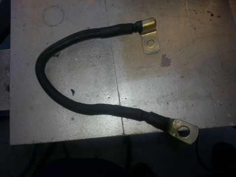 1994 Ford Bronco - A single battery cable is shown on a metallic surface, with visible text indicating a part number or date.