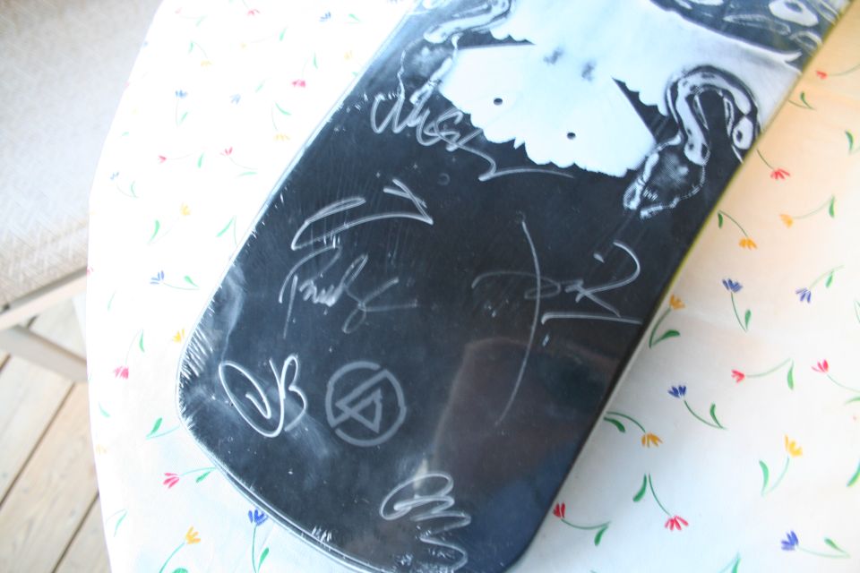 Black skateboard with white signatures and graphic