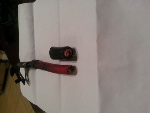 1994 Ford Bronco - Close-up of two severed battery cables, one of which has red insulation on its end.