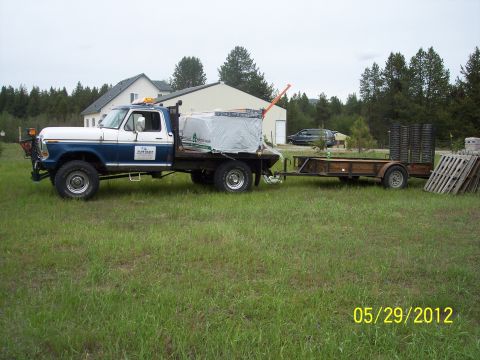 1973 Ford F-250 - This truck is hauling a trailer loaded with materials and equipment, parked on a grassy area.