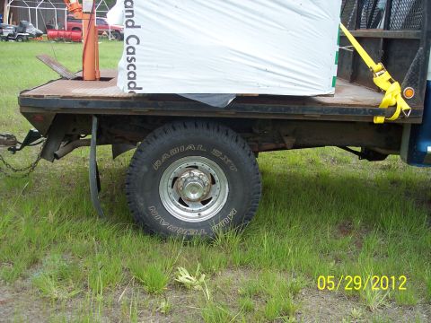 1973 Ford F-250 - A flatbed truck is seen from the side, carrying a large load of white material.