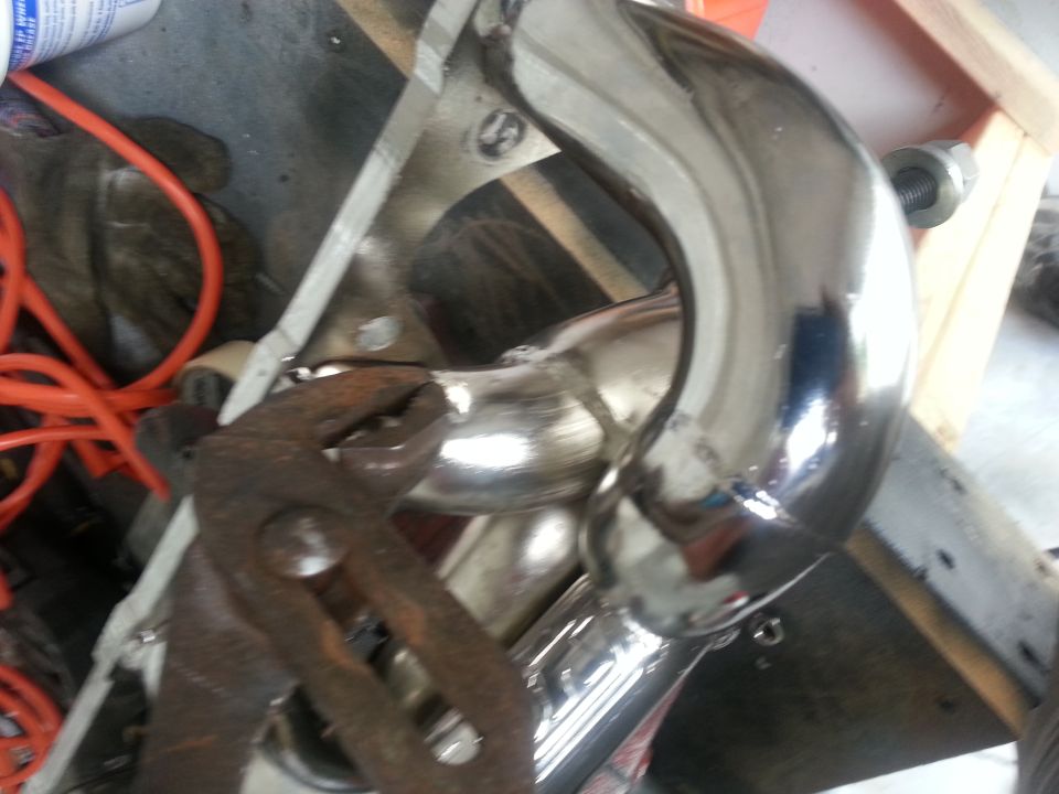 Chrome exhaust pipe with rusty pliers on it, next to an orange cord