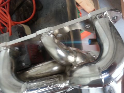 1994 Ford Bronco - A chrome exhaust manifold is being welded with a blue flame torch.