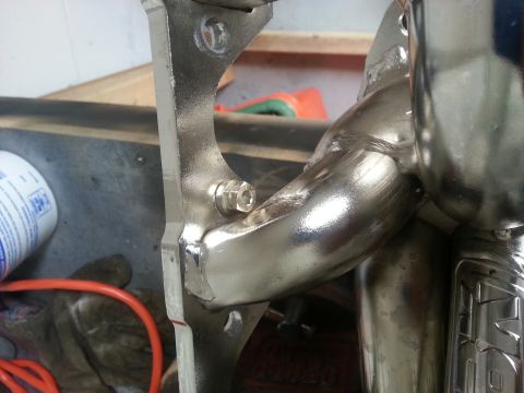 1994 Ford Bronco - Close-up view of a shiny exhaust manifold with a bolted bracket. Text from Supermotors.net is visible.