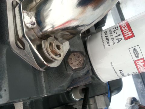 1994 Ford Bronco - Close-up of an oil filter and exhaust manifold bolt on an engine block.