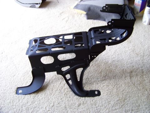 1999 Mercury Grand Marquis - A black metal car seat frame is shown on a carpeted floor, with some other car parts in the background.