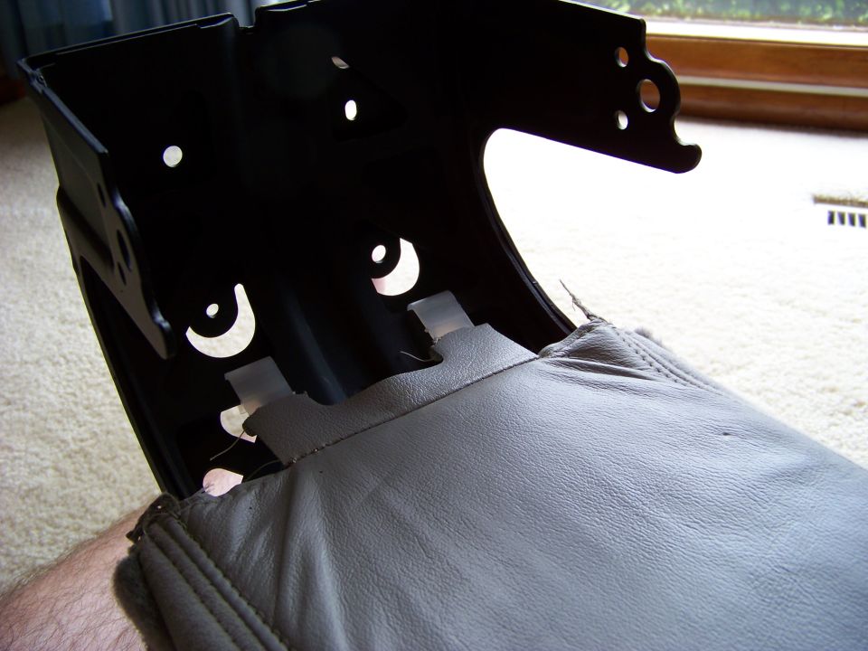 Close-up of a gray leather car seat part with black metal bracing