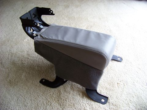 1999 Mercury Grand Marquis - A gray leather center console armrest with visible mounting hardware is shown against a carpeted background.