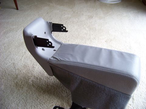 1999 Mercury Grand Marquis - A gray center console armrest with visible black mounting brackets is shown against a carpeted background.