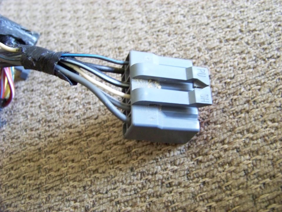 Gray plastic wiring harness connector with multiple wires, some taped