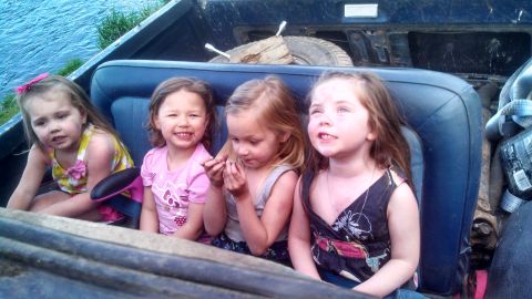 1979 Ford Bronco - Four young girls are seated in the back of a pickup truck, enjoying a day outdoors.