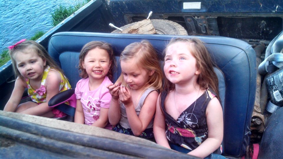 Four girls in a pickup truck bed, one with a pink bow