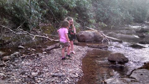 1979 Ford Bronco - Two young girls explore a rocky stream bed surrounded by trees and foliage.