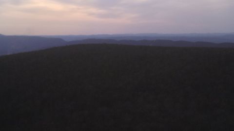 1979 Ford Bronco - A vast landscape of rolling hills fades into the distance under a dusky sky, with a website logo visible.