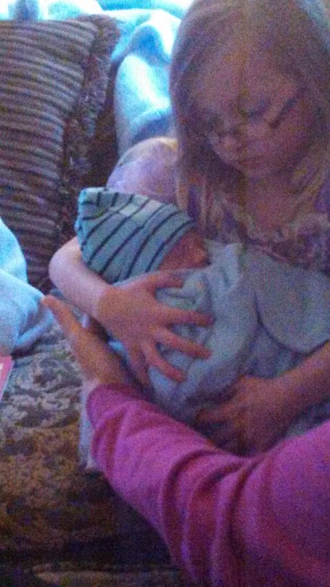 1979 Ford Bronco - A tender moment captured as two individuals cradle a newborn baby, who is dressed in a blue striped hat and blanket.